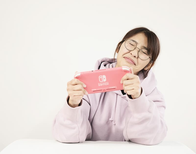 休日のK.Y.さん。パーカー姿で携帯ゲーム機を構えている