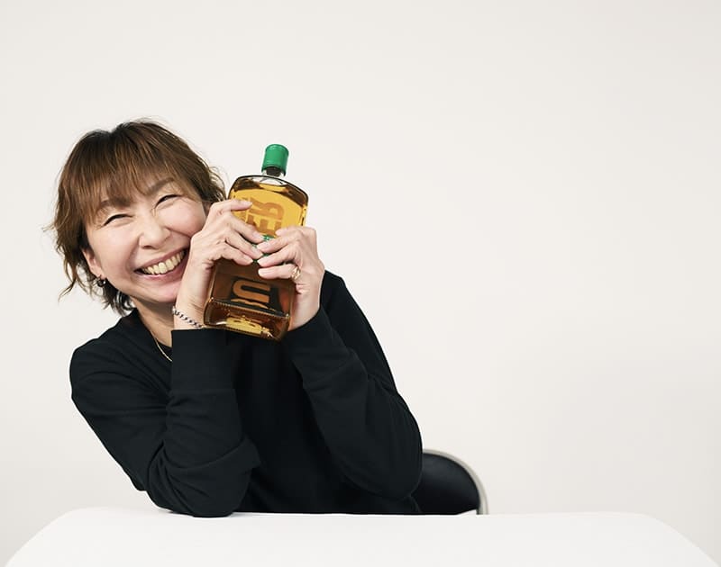 休日のK.Y.さん。ウイスキーの瓶を抱えて笑っている